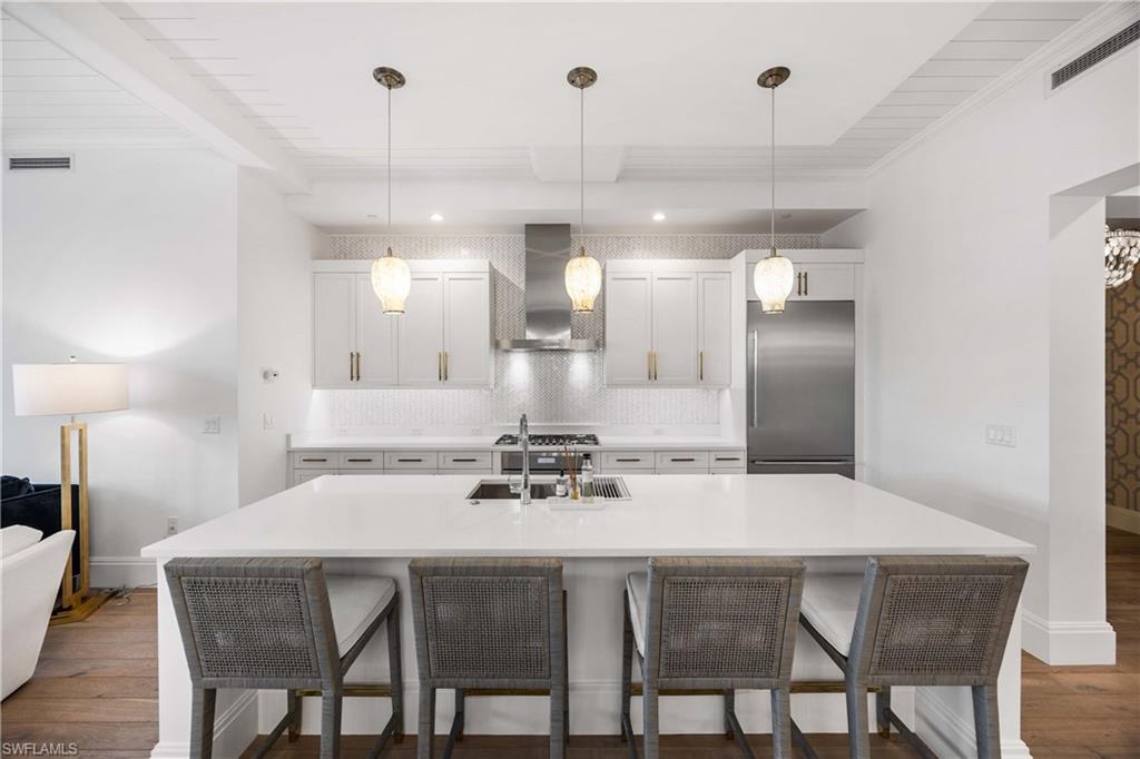 875 6th Avenue South, Unit 203 Naples, FL 34102 - Photo 3 of 49 Kitchen with a kitchen bar, built in fridge, wall chimney exhaust hood, dark wood-type flooring, and ornamental molding