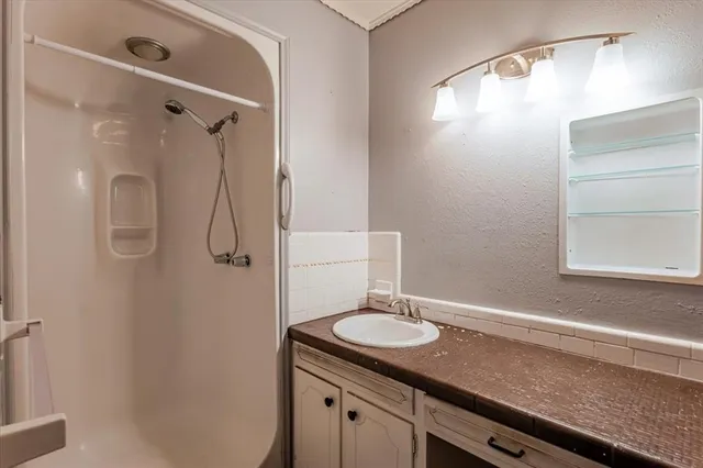 a bathroom with a granite countertop sink a shower and a mirror