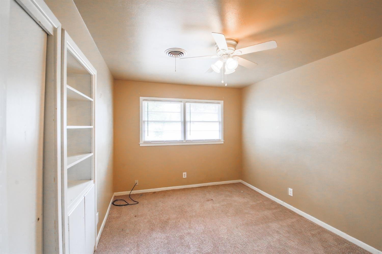 3809 25th Street Lubbock, TX 79410 - Photo 4 of 8 an empty room with a window and a fan