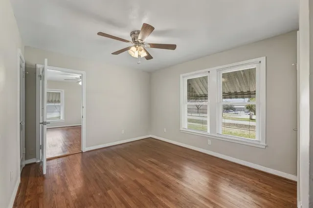 a view of an empty room with a window and wooden floor