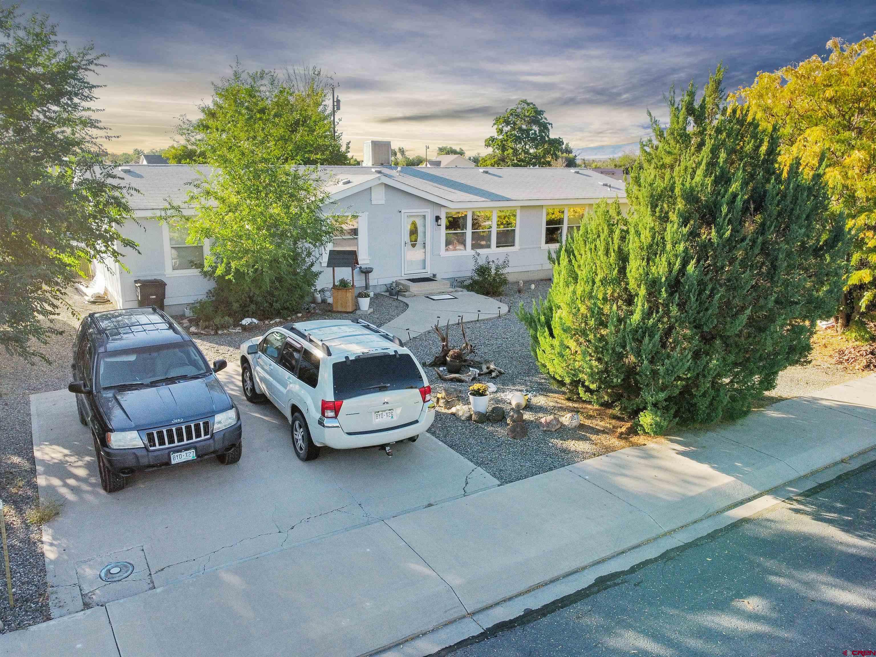 a front view of a house with a garden and parking area