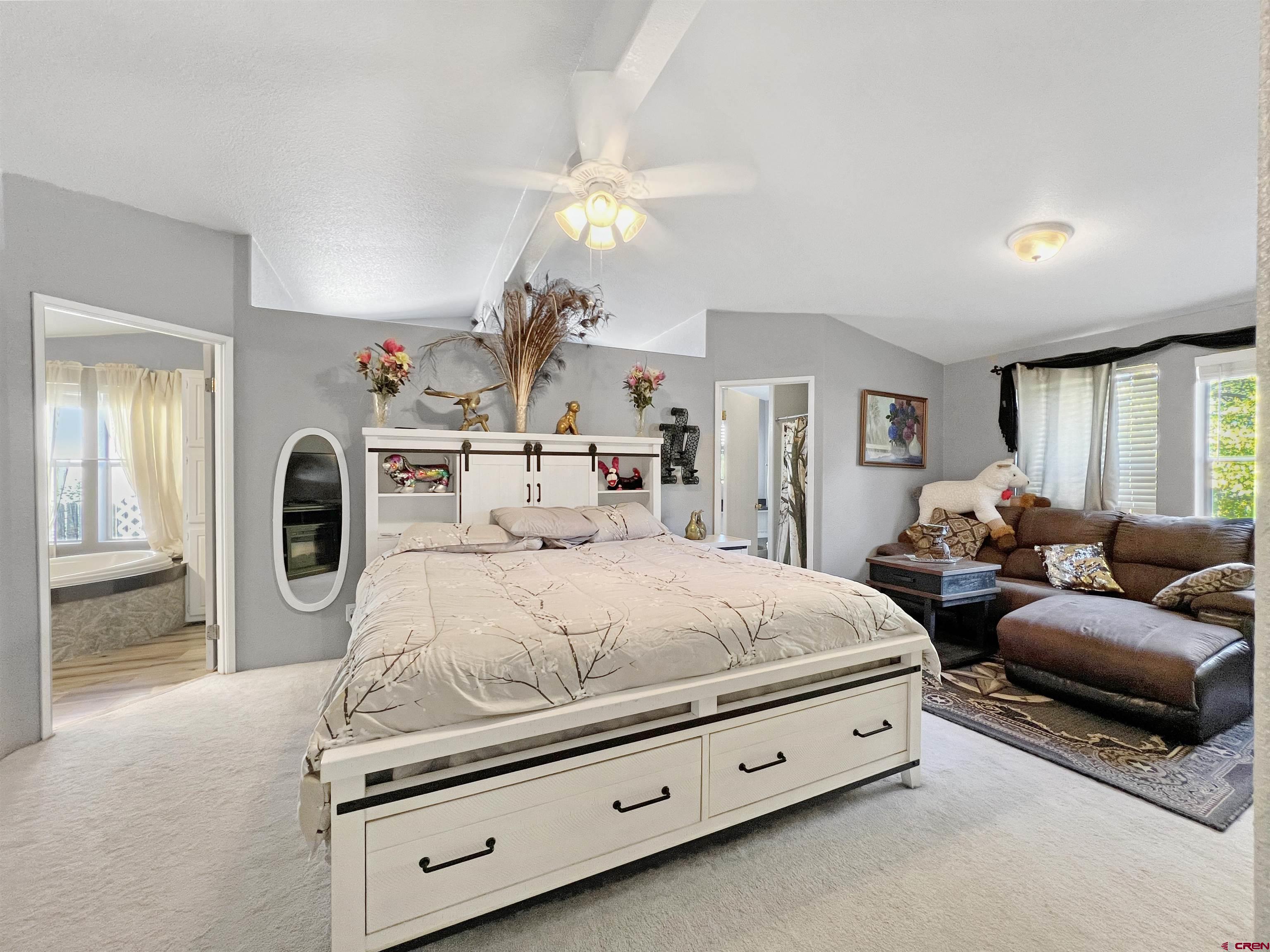 635 Fox Court Delta, CO 81416 - Photo 10 of 22 a spacious bedroom with a bed a mirror on dresser and a chandelier