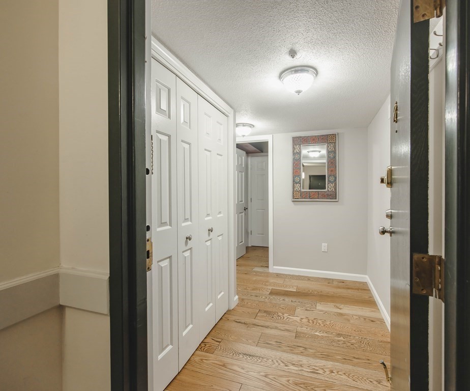 59 Brainerd Road, Unit 407 Boston, MA 02134 - Photo 2 of 22 a view of a hallway with wooden floor and a bathroom