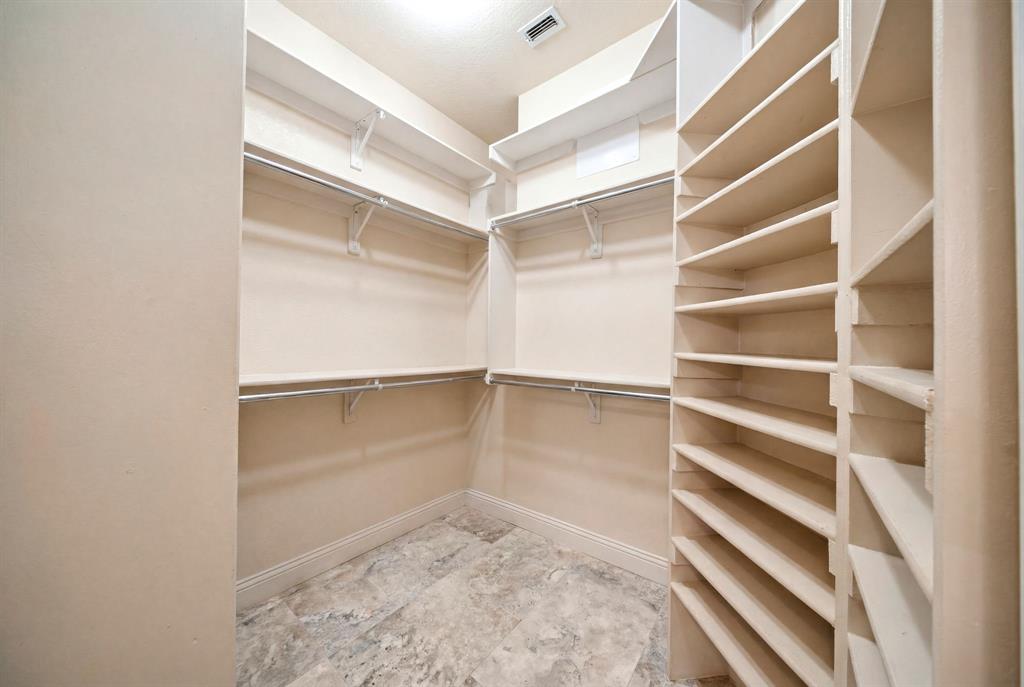 600 Aspen Street Pilot Point, TX 76258 - Photo 13 of 39 Walk-in closet featuring extensive built-in shelving, multiple hanging rods, durable tile flooring, and recessed ceiling lighting