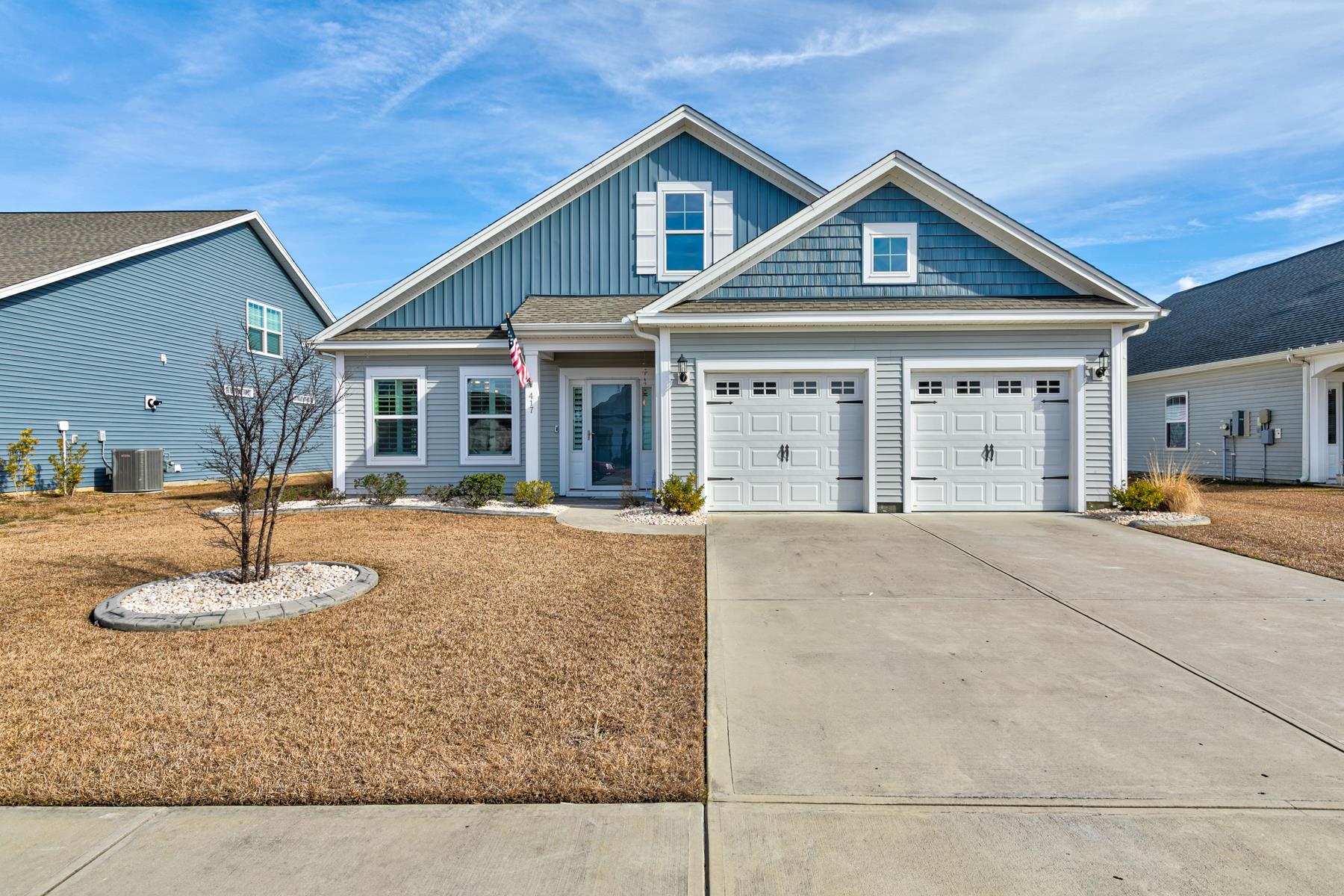 View of front facade featuring board and batten siding, driveway, and a garage