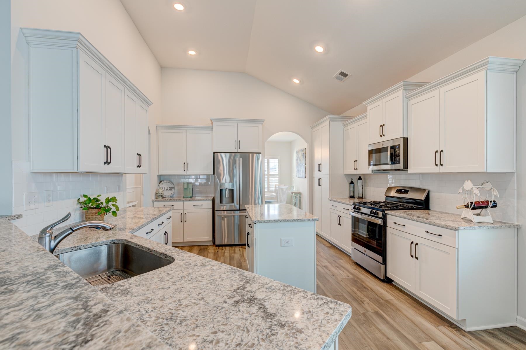 417 Heathside Street Murrells Inlet, SC 29576 - Photo 11 of 40 Kitchen featuring arched walkways, stainless steel appliances, vaulted ceiling, white cabinetry, and decorative backsplash