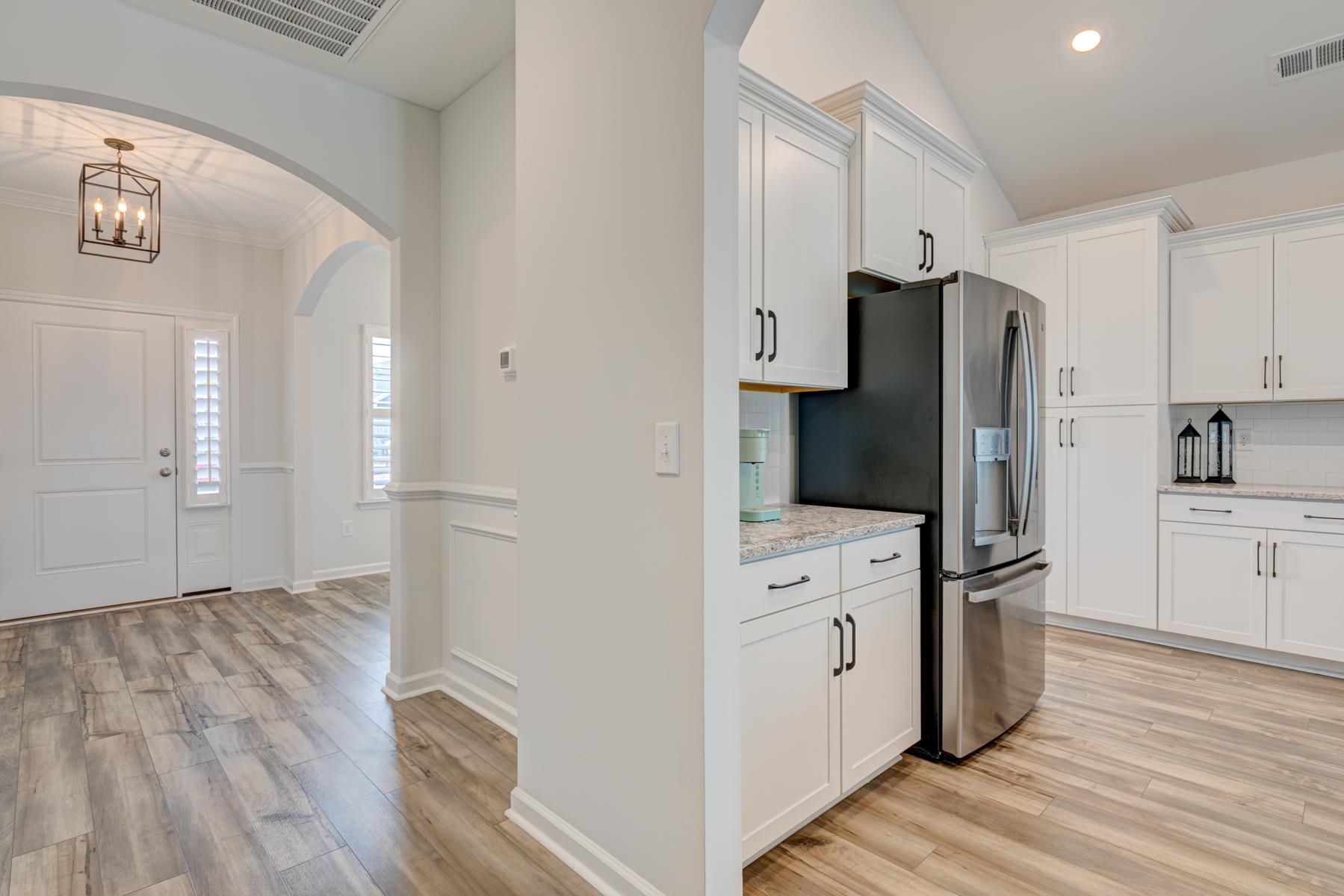 417 Heathside Street Murrells Inlet, SC 29576 - Photo 8 of 40 Kitchen with arched walkways, light wood finished floors, white cabinets, stainless steel fridge, and recessed lighting
