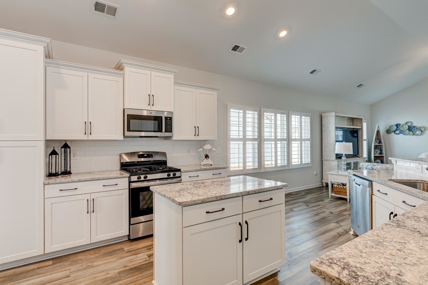 417 Heathside Street Murrells Inlet, SC 29576 - Photo 9 of 40 Kitchen featuring a center island, appliances with stainless steel finishes, white cabinetry, light stone counters, and light wood finished floors