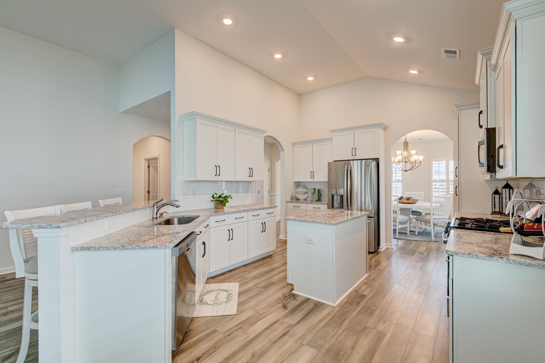 417 Heathside Street Murrells Inlet, SC 29576 - Photo 10 of 40 Kitchen featuring arched walkways, decorative backsplash, a peninsula, light stone countertops, and light wood-type flooring