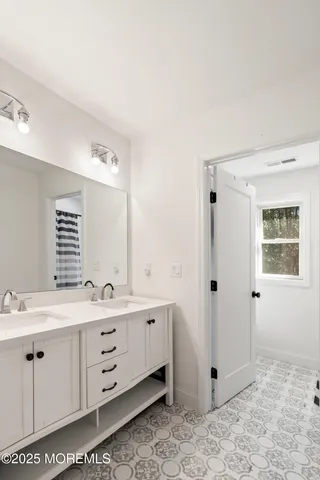 a view of bathroom with double vanity sink a mirror and a shower