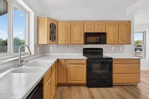 an empty room with wooden floor fireplace and windows