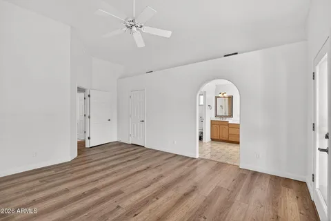 an empty room with wooden floor fireplace and windows