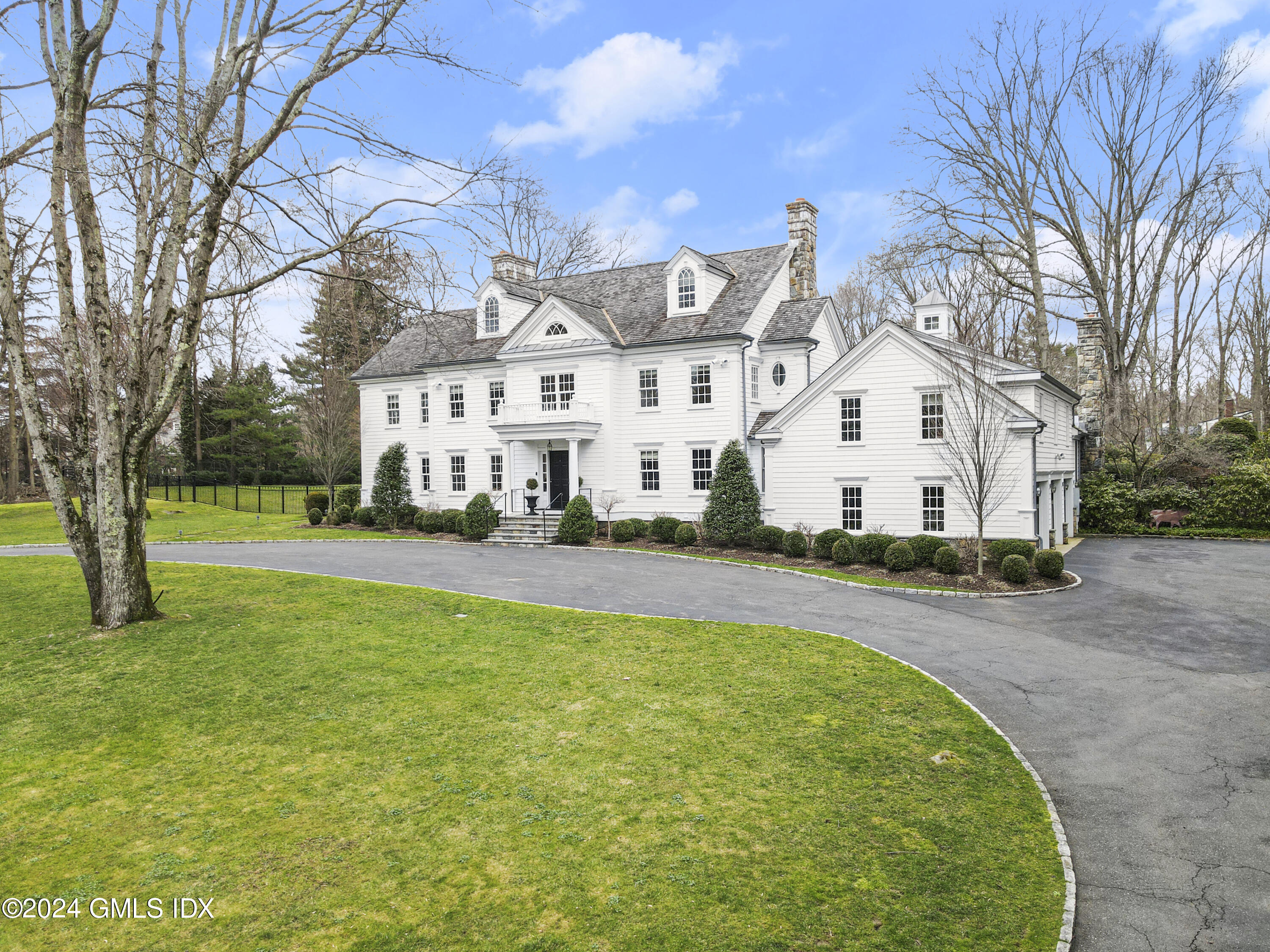 a view of a white house with a big yard and large trees
