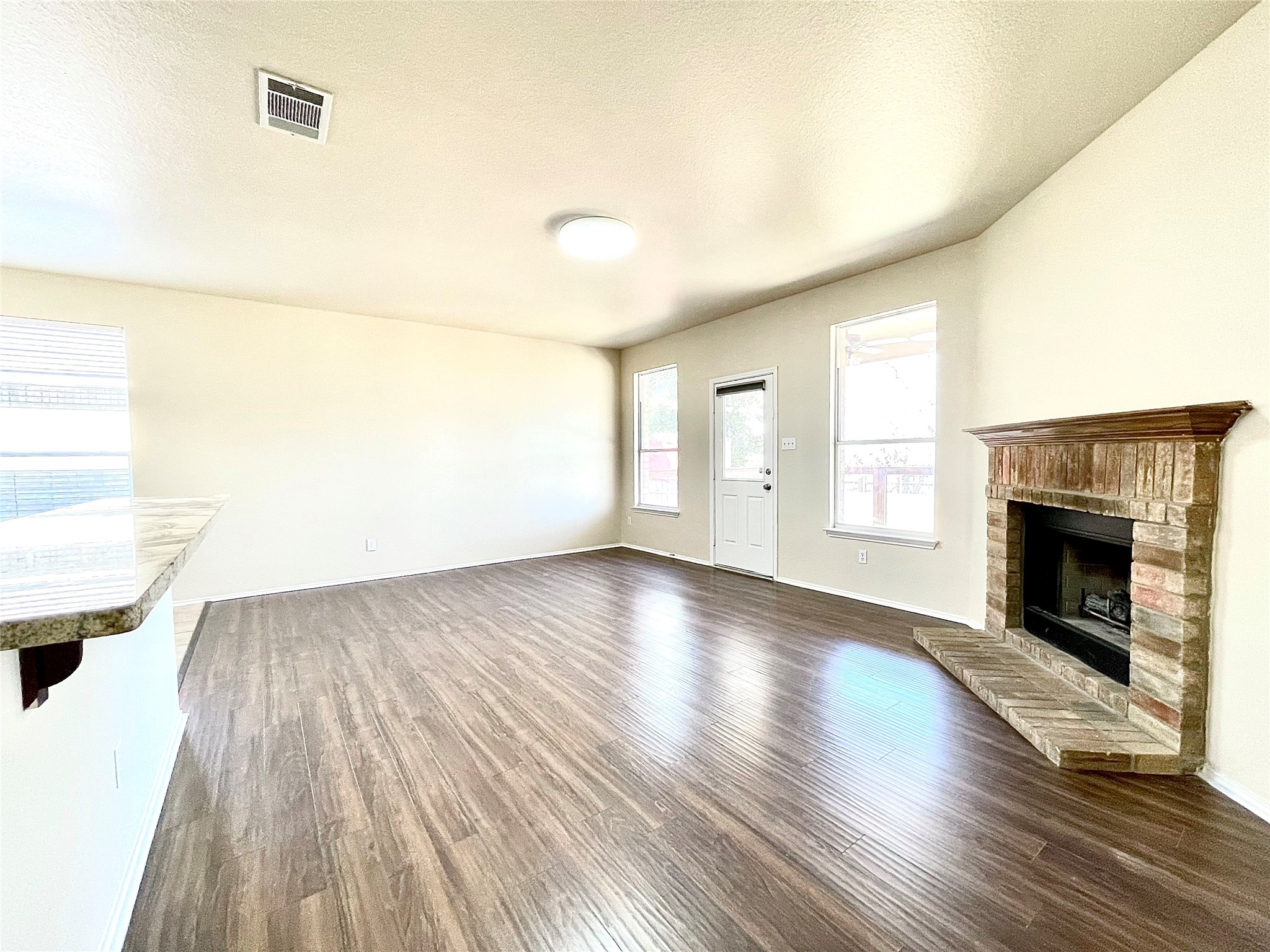 508 Emma Rose Trail Leander, TX 78641 - Photo 30 of 40 A spacious living area featuring rich wood flooring and a classic brick fireplace.