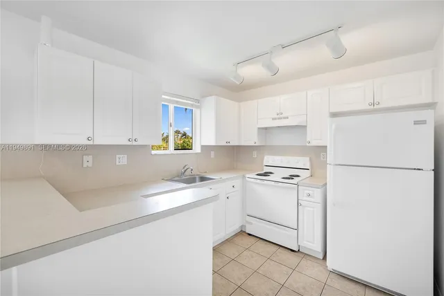 a kitchen with a sink a refrigerator and white cabinets