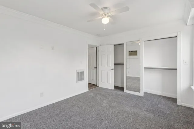 an empty room with closet and a ceiling fan