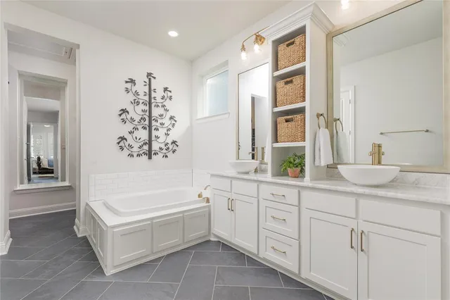 a spacious en suite bathroom with a double vanity sink a mirror a bathtub and