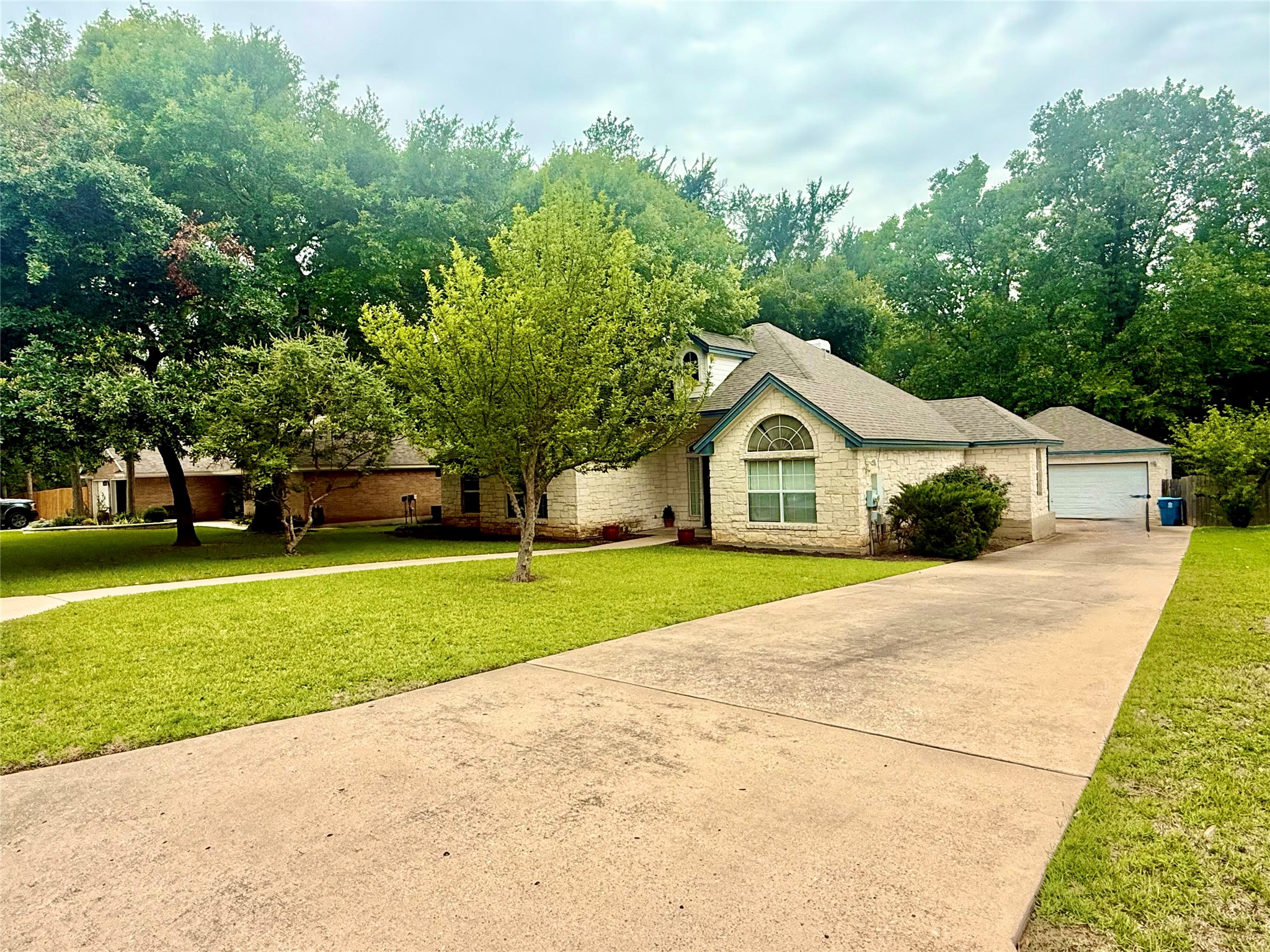 1127 Robin Road Elgin, TX 78621 - Photo 17 of 19 View of front facade with stone siding, a front lawn, a detached garage, an outdoor structure, and roof with shingles