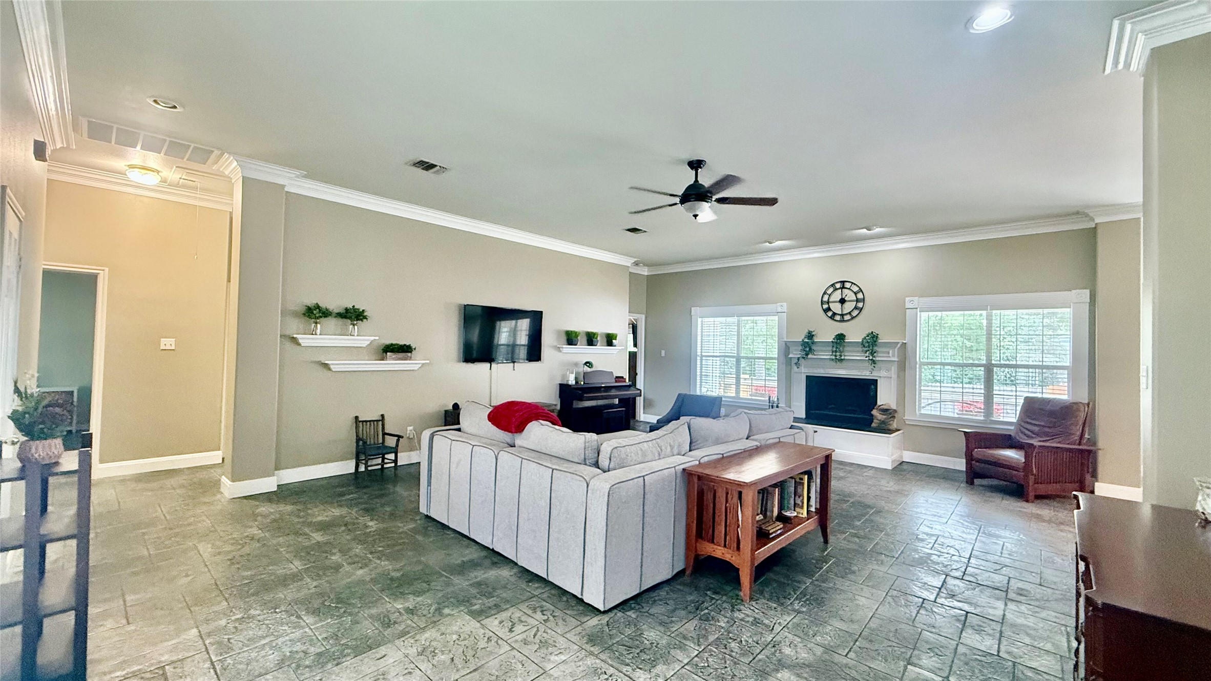 1127 Robin Road Elgin, TX 78621 - Photo 3 of 19 Living room with stone tile flooring, ceiling fan, baseboards, a fireplace with raised hearth, and ornamental molding