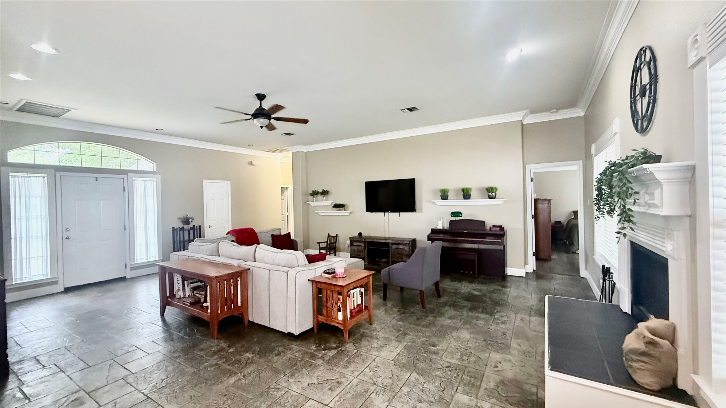 1127 Robin Road Elgin, TX 78621 - Photo 4 of 19 Living area with a fireplace with raised hearth, a ceiling fan, crown molding, stone tile flooring, and baseboards