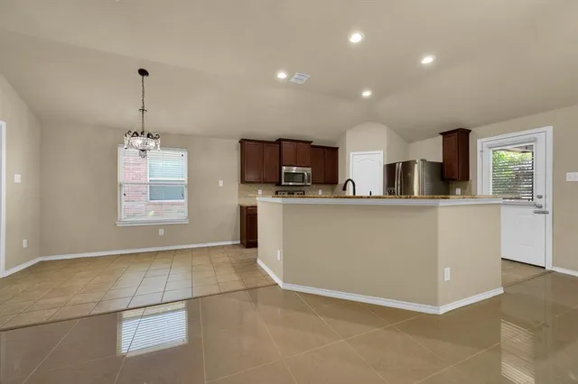 a kitchen with stainless steel appliances kitchen island granite countertop a stove top oven a sink dishwasher and a refrigerator