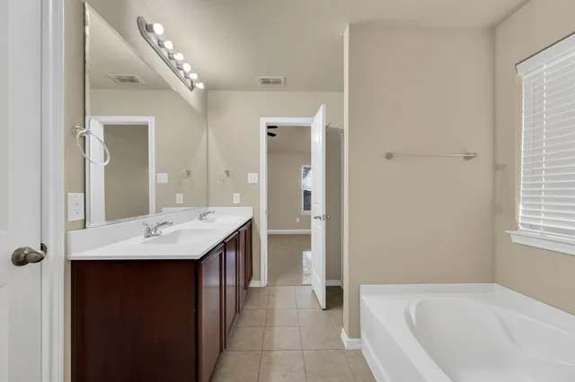 a bathroom with a granite countertop sink a bathtub and a mirror