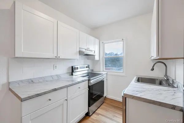 a kitchen with a sink dishwasher and cabinets with wooden floor