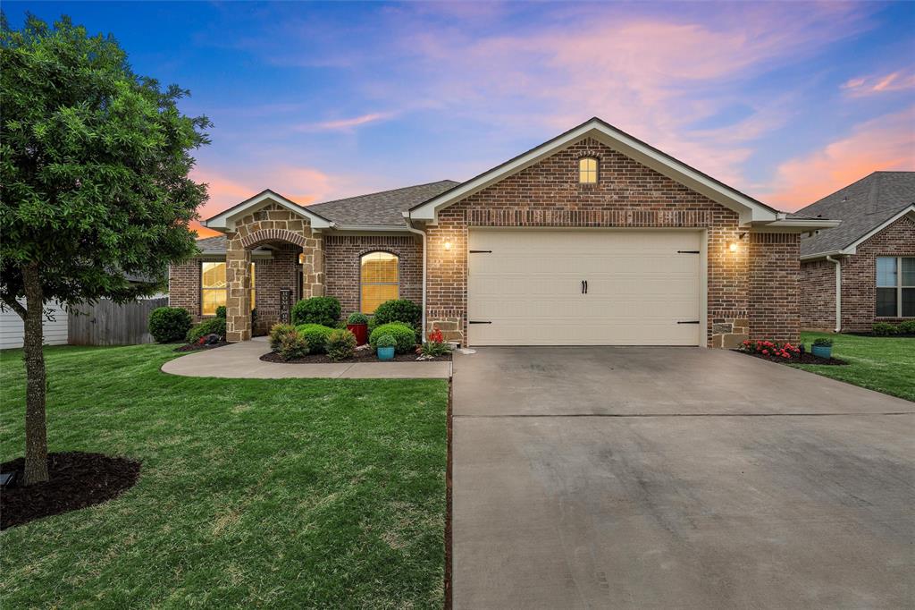French country home with brick siding, driveway, a garage, and roof with shingles