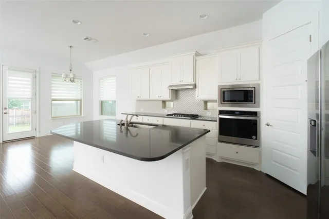 a kitchen with stainless steel appliances granite countertop a sink a stove and a refrigerator
