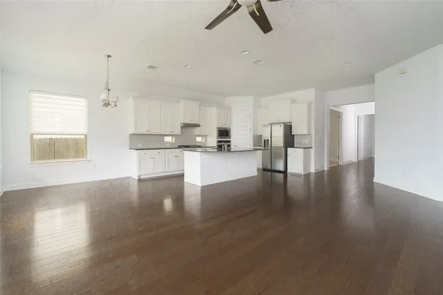 a kitchen with stainless steel appliances granite countertop a stove top oven a sink dishwasher and a refrigerator with wooden floor