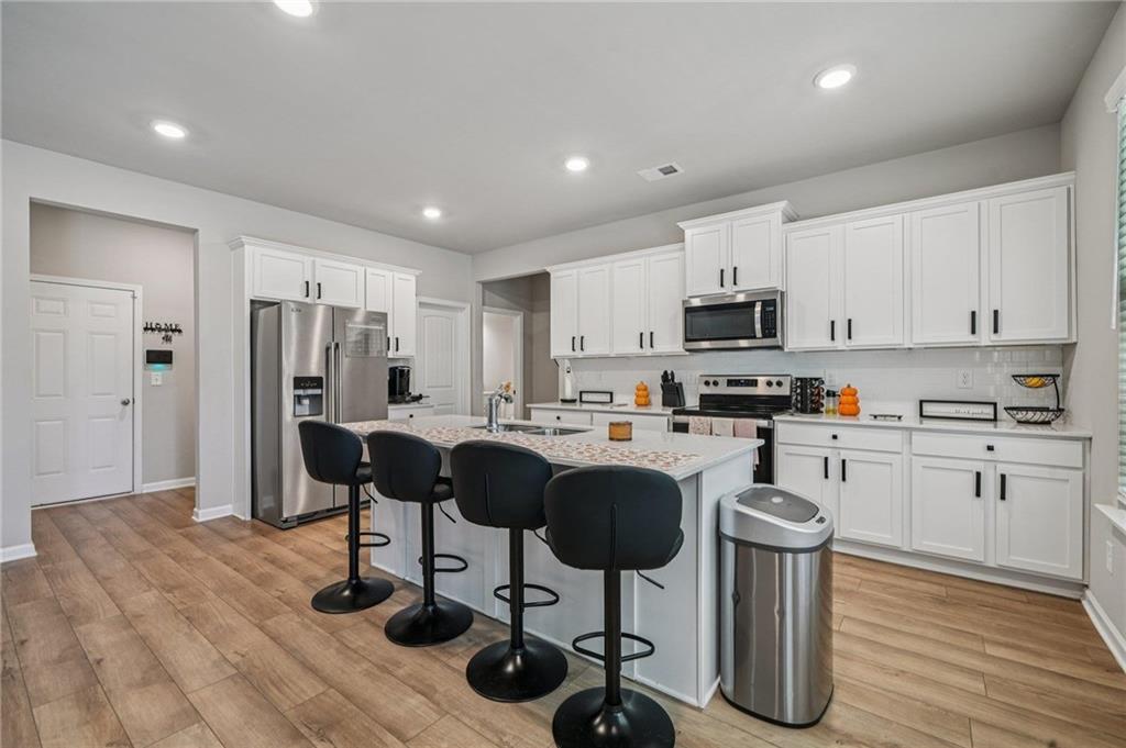 120 Cabin Way Hampton, GA 30228 - Photo 11 of 51 a kitchen with stainless steel appliances granite countertop a refrigerator a stove a sink dishwasher and white cabinets with wooden floor