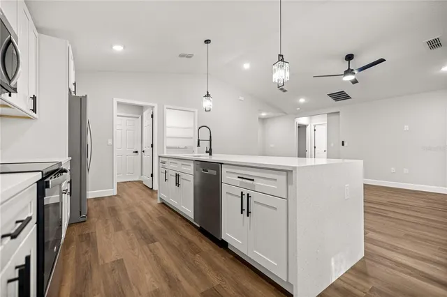 a kitchen with a sink chandelier and wooden floor