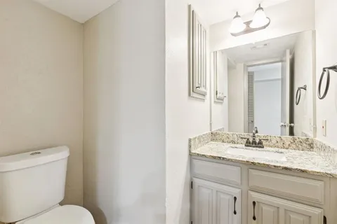 a bathroom with a granite countertop sink mirror and toilet