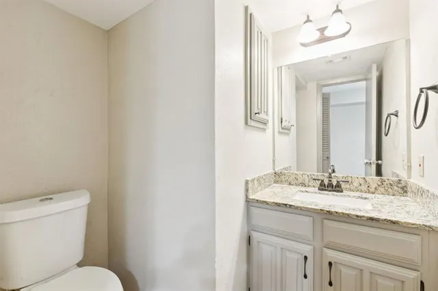 a bathroom with a granite countertop sink mirror and toilet