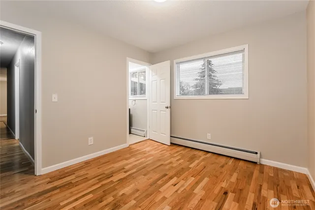 an empty room with wooden floor closet and windows