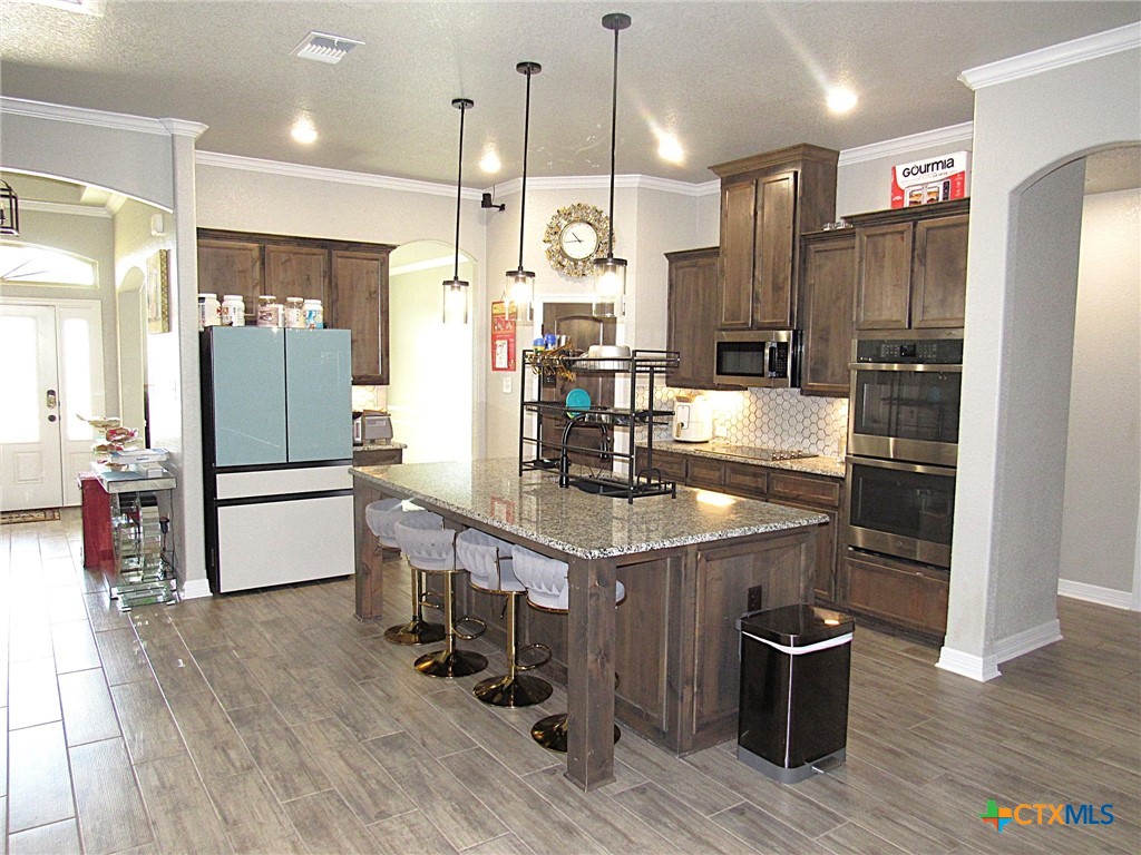 7606 Palladium Loop Killeen, TX 76542 - Photo 5 of 28 a kitchen with stainless steel appliances granite countertop a refrigerator a stove and a wooden floors
