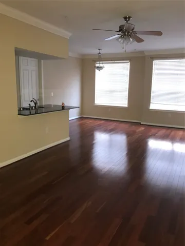 a view of empty room with wooden floor and fan