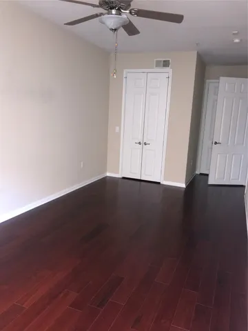 an empty room with wooden floor fan and windows