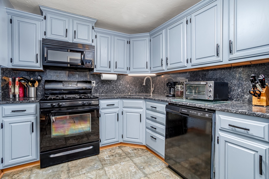 107 Ridgefield Circle, Unit D Clinton, MA 01510 - Photo 3 of 37 a kitchen with stainless steel appliances granite countertop a stove a microwave and cabinets