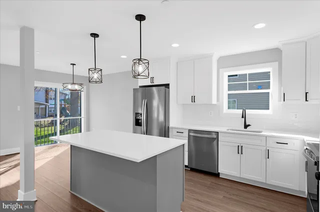 a kitchen with stainless steel appliances a sink a window a wooden floor and cabinets