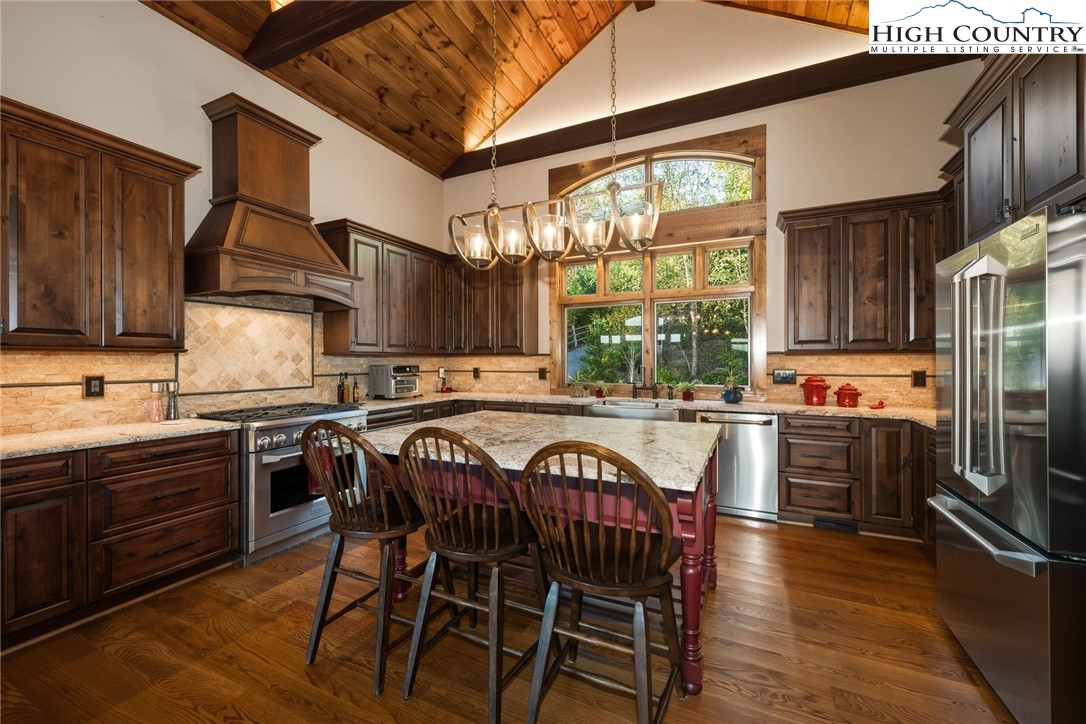 550 Big Sky Road Ferguson, NC 28624 - Photo 12 of 35 a kitchen with stainless steel appliances granite countertop a stove a refrigerator a sink a dining table and chairs with wooden floor