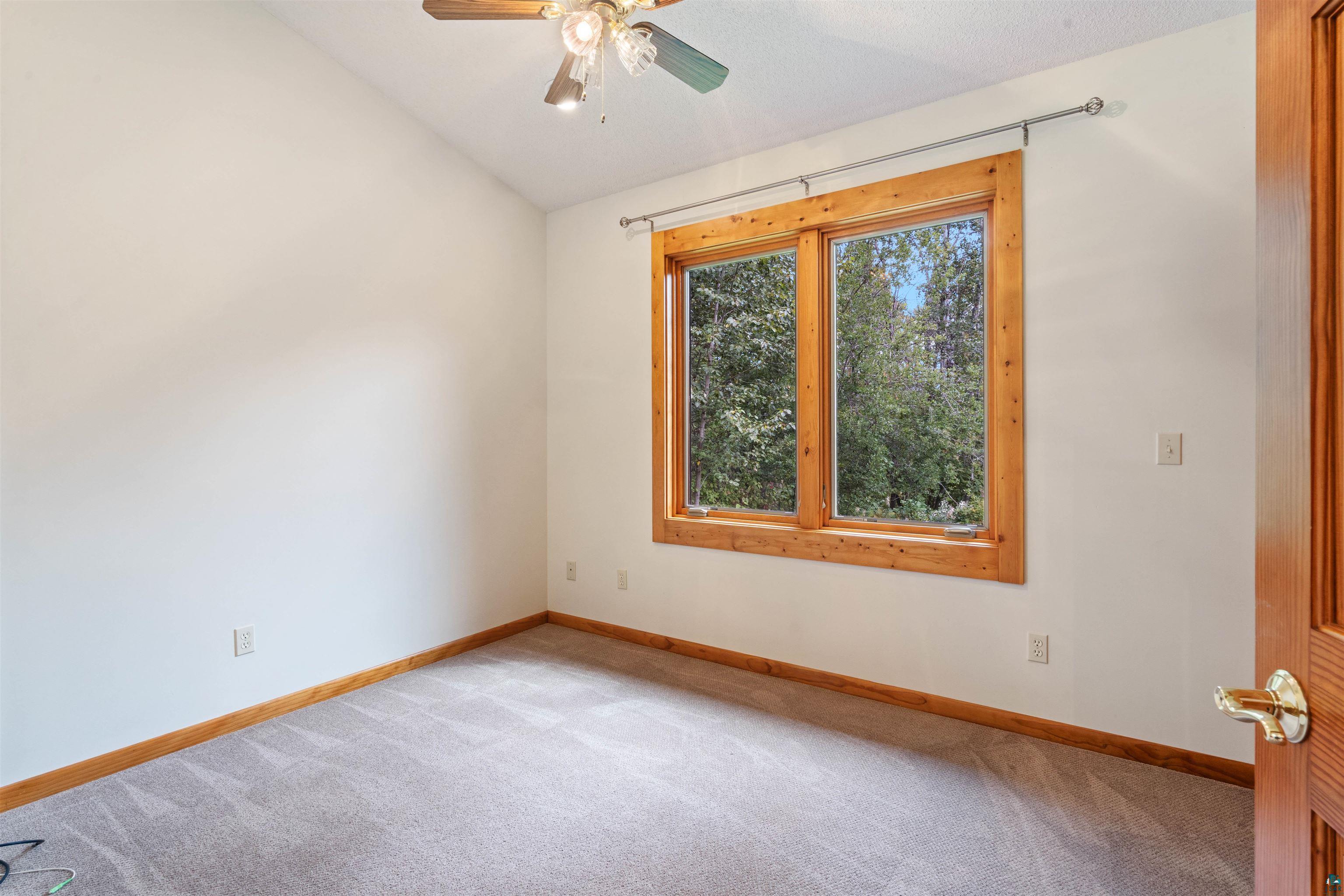5373 Lester River Road Duluth, MN 55804 - Photo 24 of 39 Carpeted flooring with wood-finish trim, wood-clad window frames, and an angled ceiling