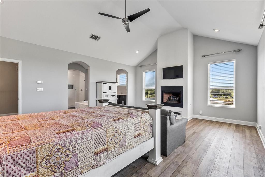 9583 Neal Road Forney, TX 75126 - Photo 11 of 34 a spacious bedroom with a large bed a flat tv screen and a fireplace
