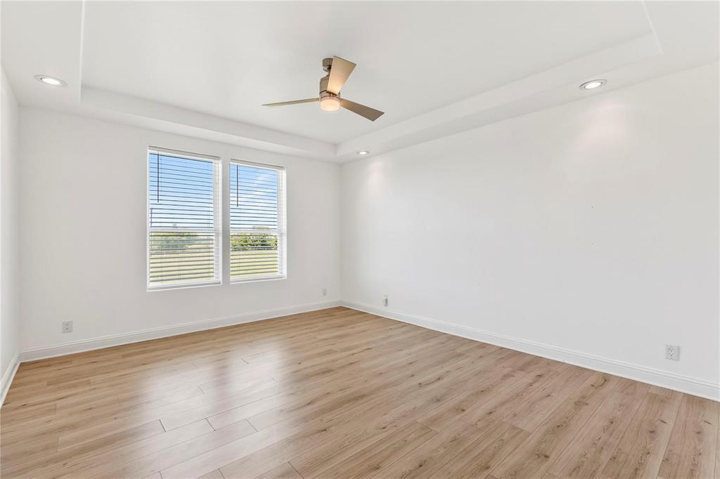 9583 Neal Road Forney, TX 75126 - Photo 18 of 34 an empty room with wooden floor chandelier fan and windows