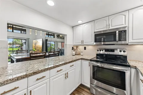a kitchen with granite countertop a stove a sink and a microwave