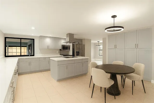 a large white kitchen with a refrigerator and microwave