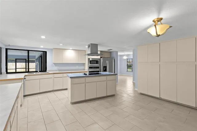 a large kitchen with stainless steel appliances a stove flat screen tv and living room view