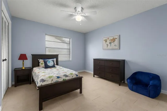 an empty room with chandelier fan and windows