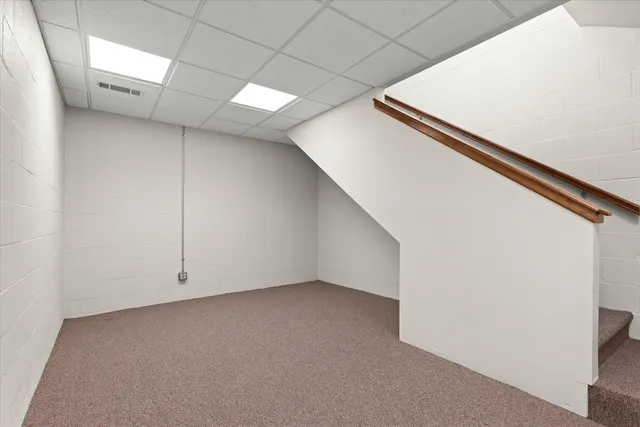 a view of an empty room with chandelier fan and wooden floor
