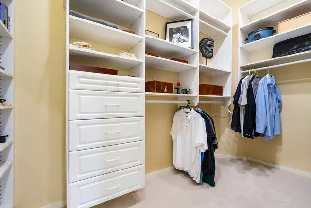 a view of walk in closet with clothes and shoes